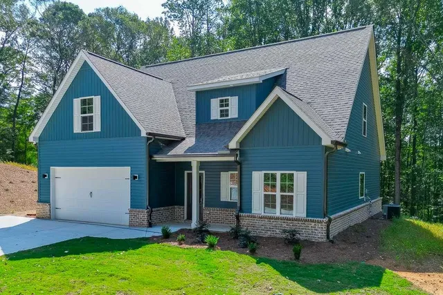 a view of a house with a yard plants and large tree