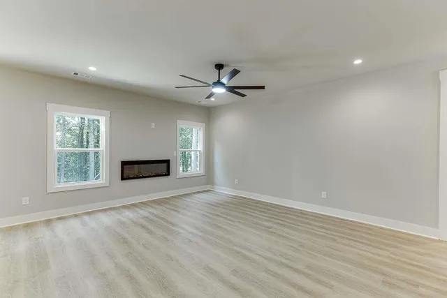 an empty room with ceiling fan and windows
