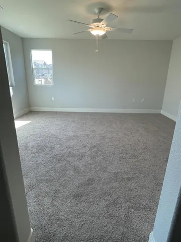 an empty room with windows and fan