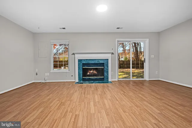 a view of empty room with a fireplace and wooden floor