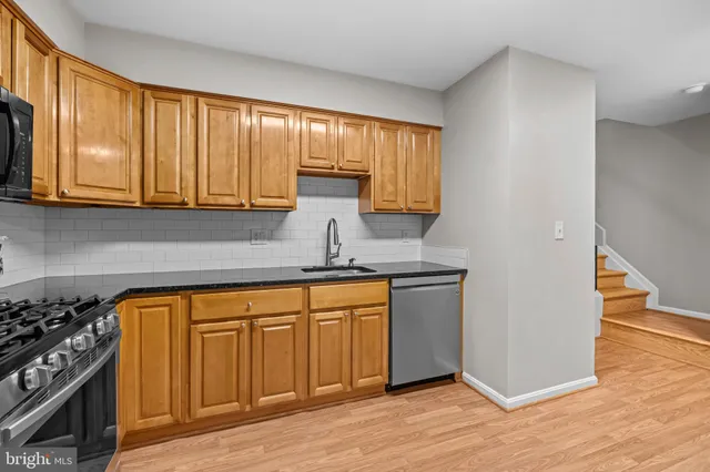 a kitchen with stainless steel appliances granite countertop a stove a sink and dishwasher with wooden cabinets
