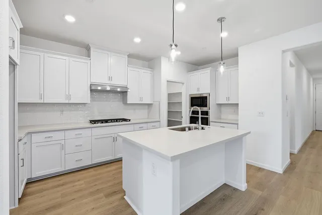 a kitchen with kitchen island a sink stainless steel appliances and white cabinets