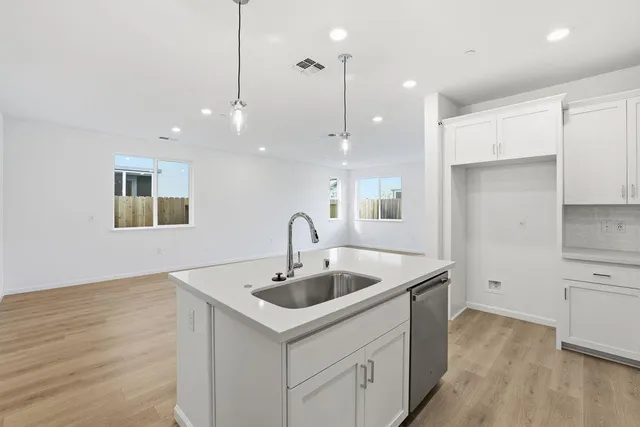 a kitchen with a sink dishwasher and a refrigerator with wooden floor