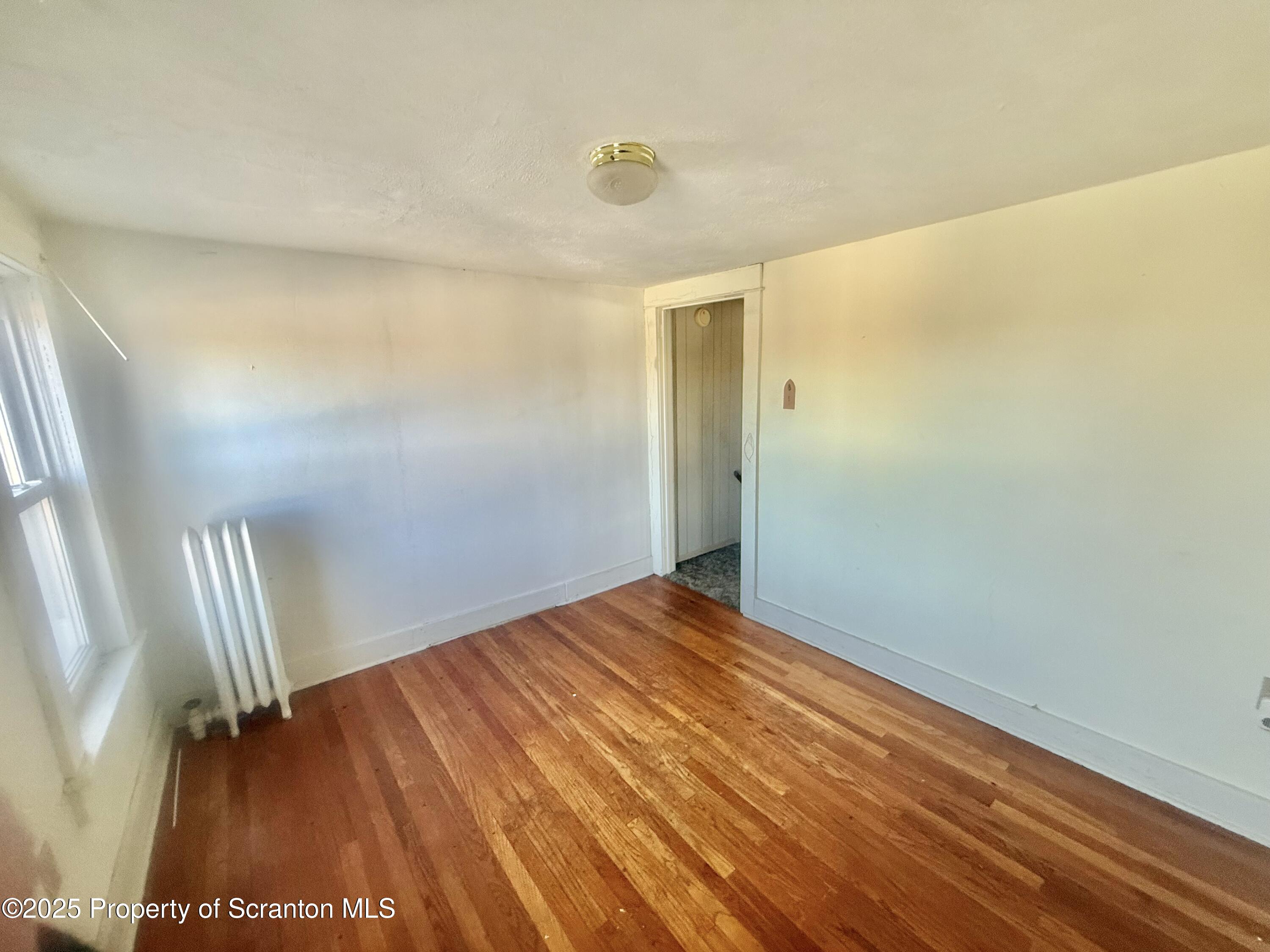 662 Simpson Street Throop, PA 18512 - Photo 6 of 9 a view of empty room with wooden floor