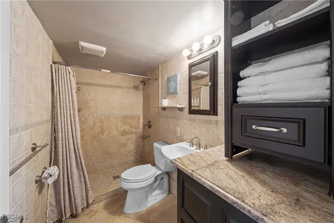 a bathroom with a granite countertop sink toilet and shower