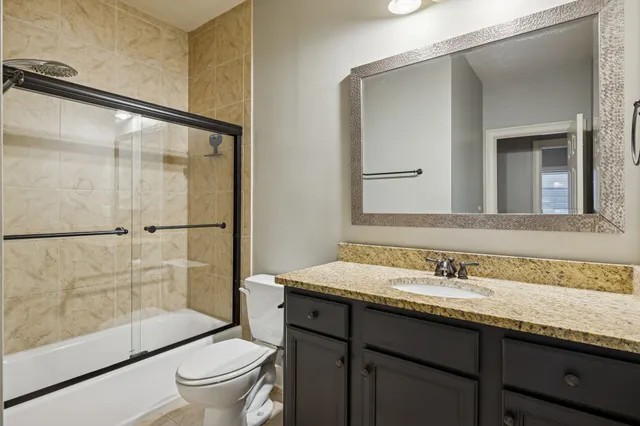 a bathroom with a granite countertop sink toilet and shower
