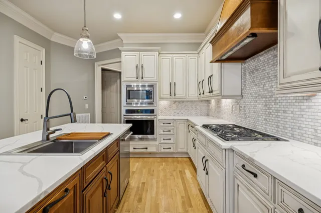 a kitchen that has a lot of cabinets a sink and appliances