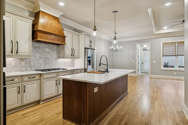 a kitchen with stainless steel appliances granite countertop a sink a stove and a wooden floors