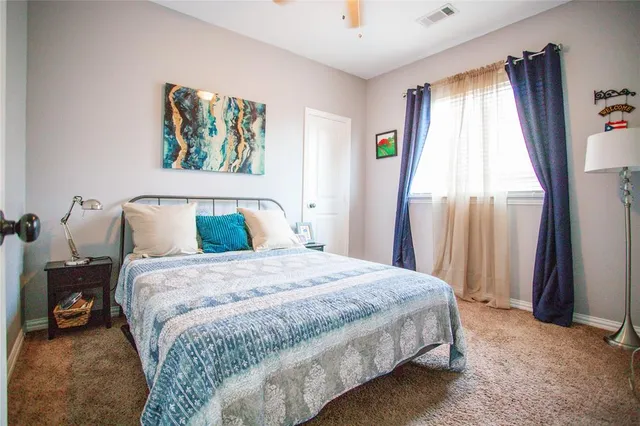 a bedroom with a bed a dresser and a chandelier