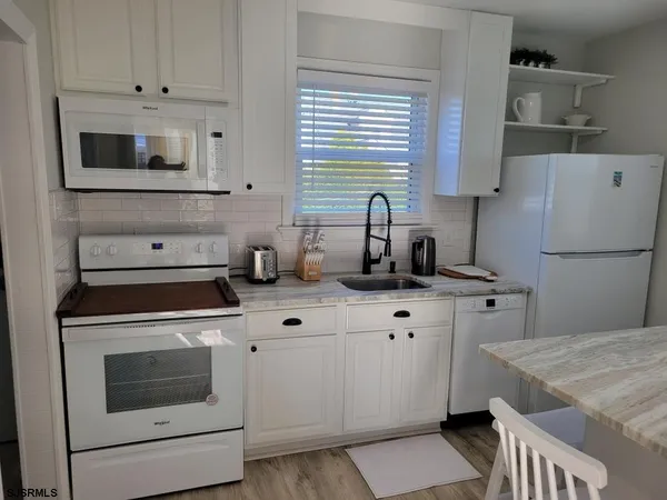 a kitchen with cabinets appliances a sink and a window