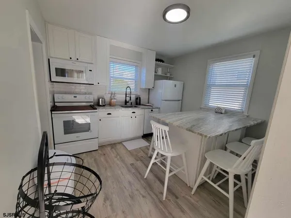 a kitchen with granite countertop a stove a sink dishwasher a dining table and chairs with wooden floor