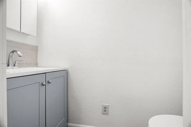 a bathroom with a sink vanity mirror and toilet