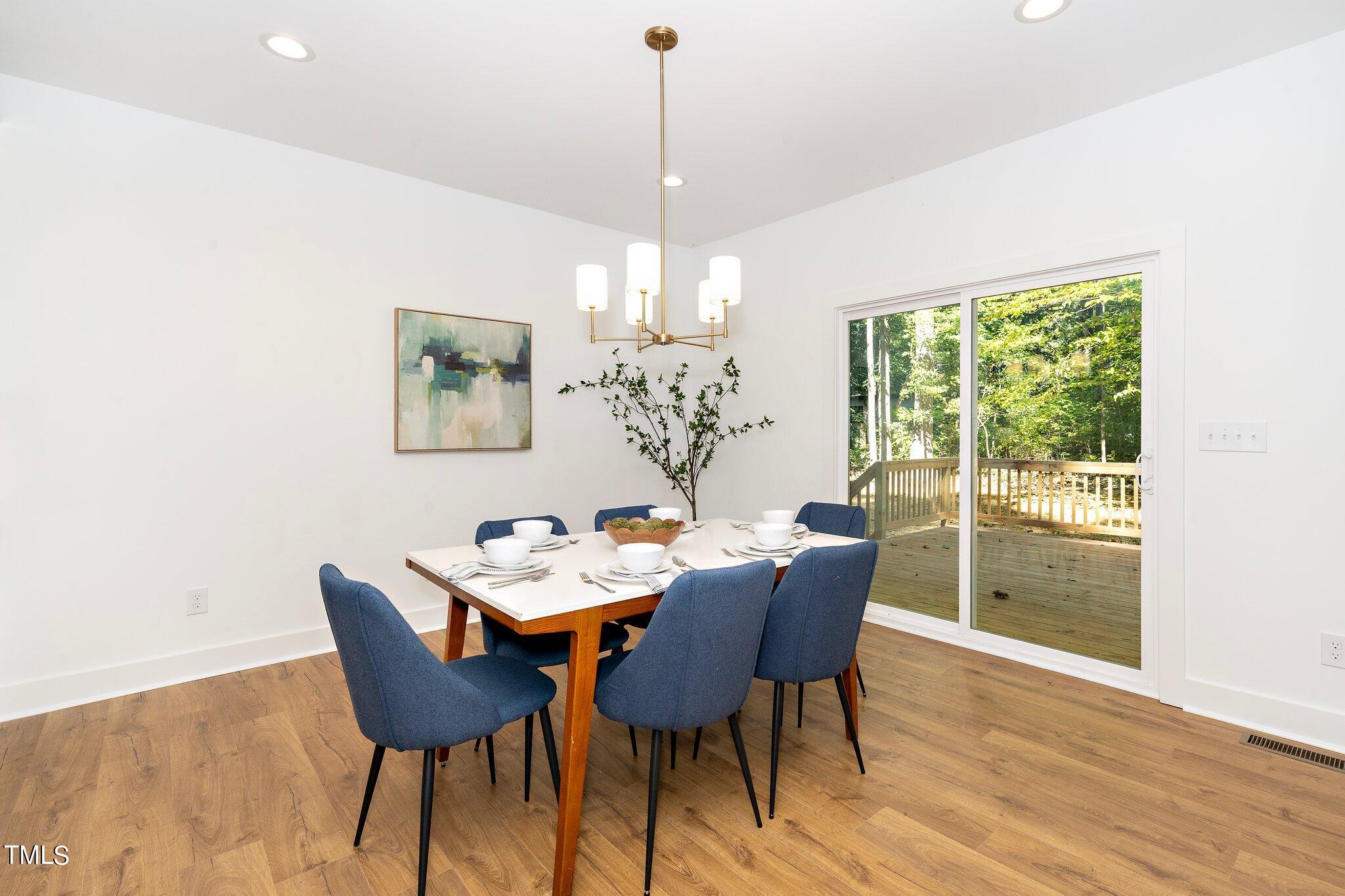 8112 Rhudy Place Raleigh, NC 27612 - Photo 14 of 39 a dining room with furniture a chandelier and wooden floor