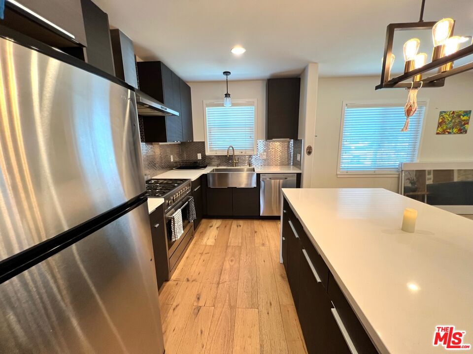 5757 Vesper Avenue Van Nuys, CA 91411 - Photo 6 of 18 a kitchen with a sink a counter top space stainless steel appliances a window and a counter space