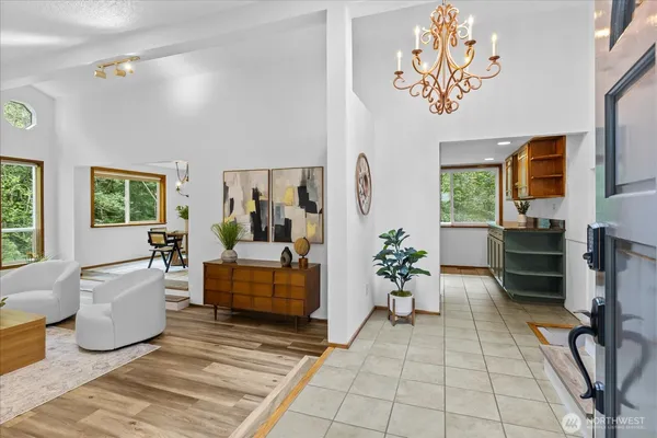 a living room with furniture a chandelier and a dining table with the potted plants