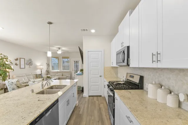 a large white kitchen with a stove a sink a dining table and chairs