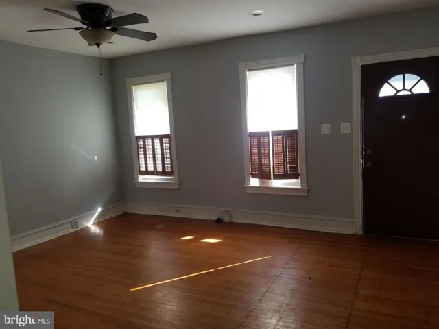 a view of an empty room with window and wooden floor
