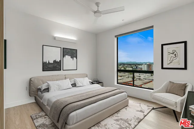 a bedroom with a large bed couch and two windows