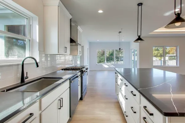 a kitchen with granite countertop a sink a counter top space appliances and cabinets