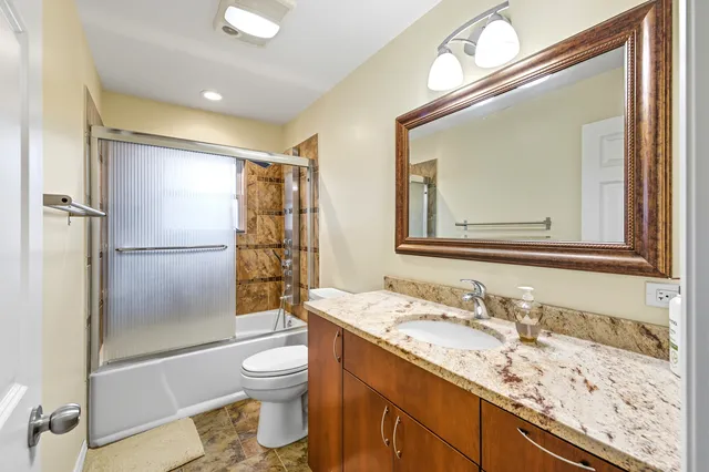 a bathroom with a granite countertop sink toilet and shower