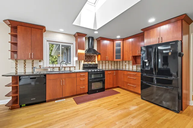 a kitchen with stainless steel appliances granite countertop a refrigerator a sink a stove and wooden cabinets