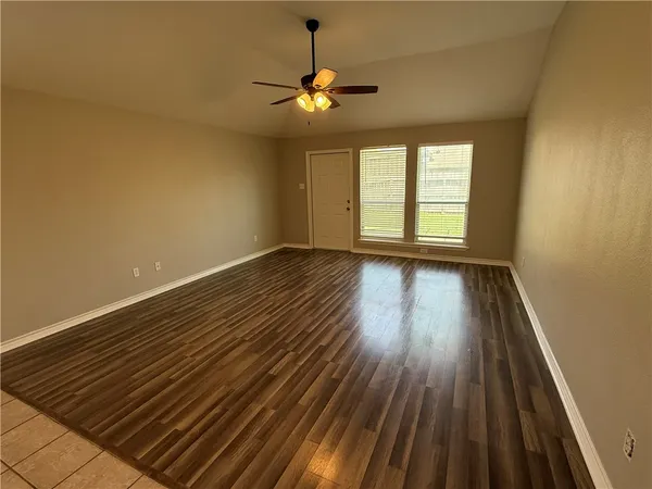 a view of an empty room with wooden floor and a window