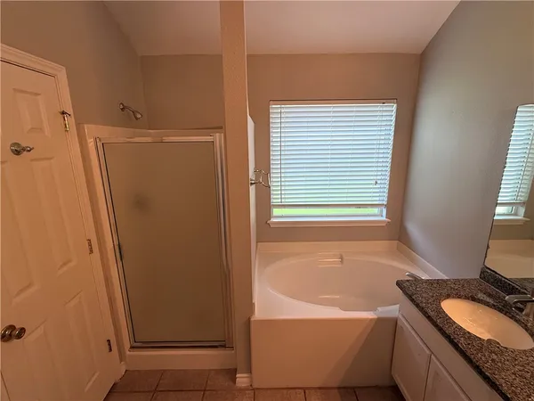 a bathroom with a granite countertop sink and a bathtub
