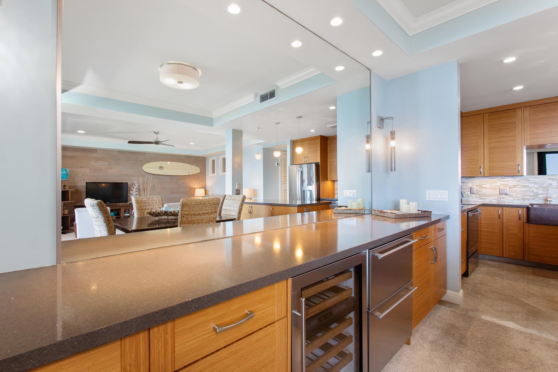 4850 Makena Alanui Road, Unit F207 Kihei, HI 96753 - Photo 13 of 34 a large kitchen with stainless steel appliances a large counter top a stove and a refrigerator with wooden floor