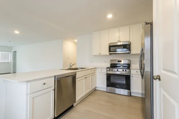 a kitchen with stainless steel appliances a refrigerator a stove a microwave and a sink