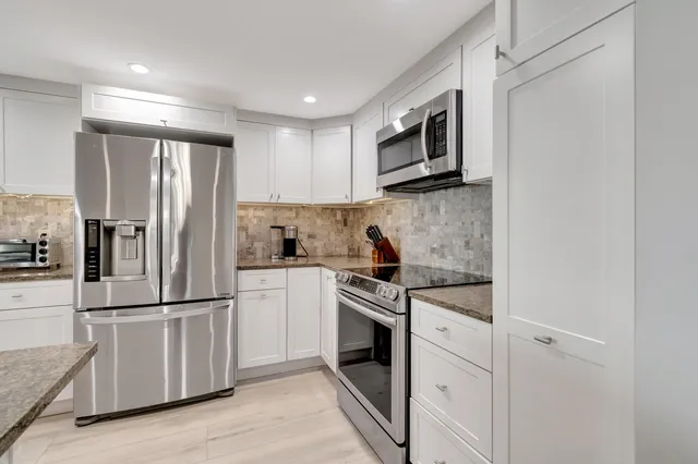 a kitchen with stainless steel appliances granite countertop a refrigerator stove and sink