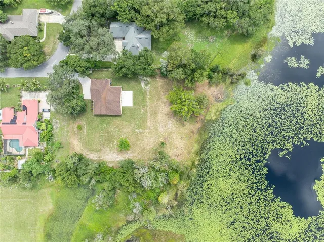 an aerial view of residential house with outdoor space and trees all around