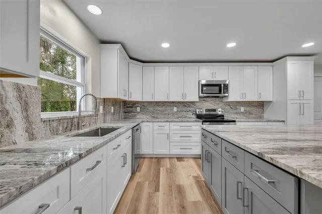 a kitchen with kitchen island granite countertop white cabinets sink and stainless steel appliances