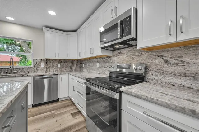 a kitchen with stainless steel appliances granite countertop a stove a sink and a microwave