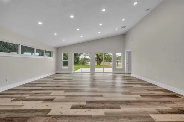 a view of empty room with wooden floor and floor to ceiling window
