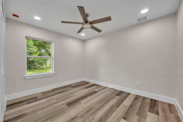 an empty room with a ceiling fan and window