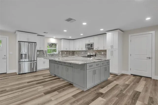 a large kitchen with kitchen island a sink stainless steel appliances and white cabinets