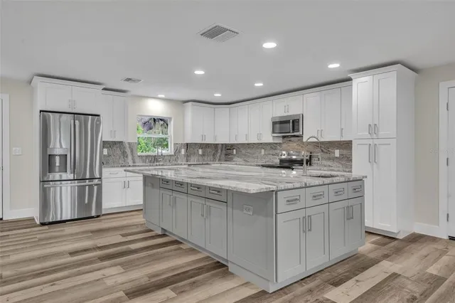 a kitchen with stainless steel appliances granite countertop a stove top oven a refrigerator a sink and a microwave