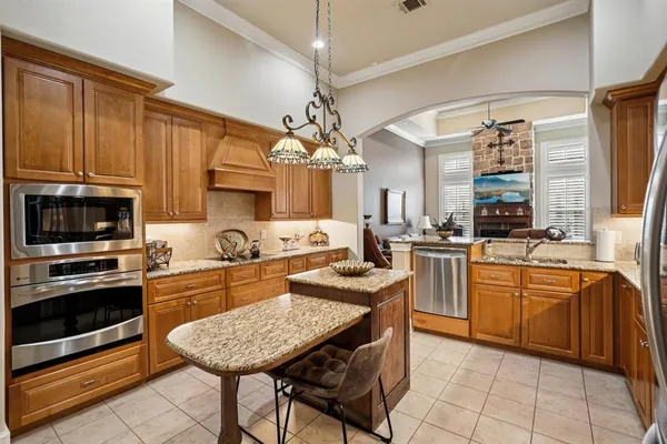 a kitchen with stainless steel appliances granite countertop a stove top oven a sink dishwasher a dining table and chairs with wooden floor