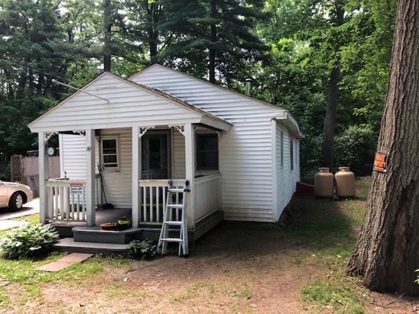 a view of a house with a yard chairs and a large tree