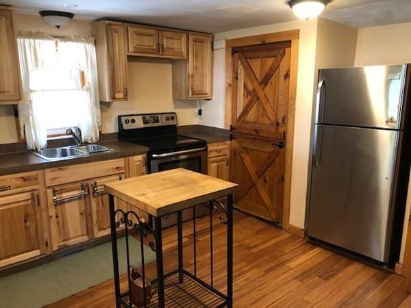 69 Pine Road Charlton, MA 01507 - Photo 19 of 26 a kitchen with stainless steel appliances granite countertop a refrigerator a sink dishwasher a stove and white countertops with wooden floor