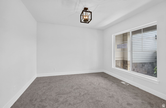 1002 West Temple Rim Lane Payson, UT 84651 - Photo 8 of 68 Bright room featuring white walls, gray carpet, a window with white trim, and a black metal lantern-style ceiling fixture