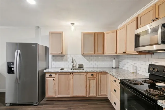 a kitchen with stainless steel appliances granite countertop a stove a sink dishwasher a refrigerator and cabinets with wooden floor