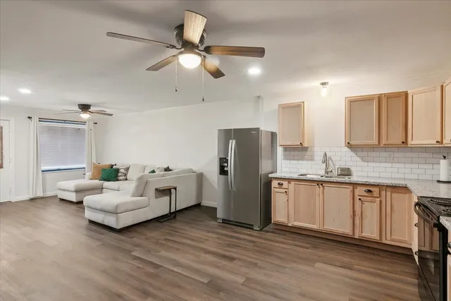 a living room with stainless steel appliances kitchen island granite countertop furniture and a refrigerator