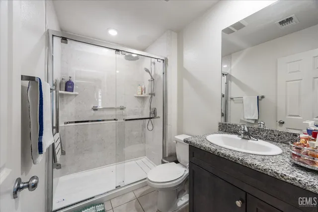 a bathroom with a granite countertop sink toilet and shower