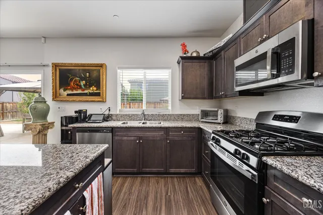a kitchen with stainless steel appliances granite countertop a stove a sink and a microwave