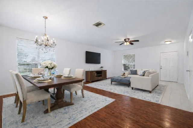 a view of a livingroom with a flat screen tv wooden floor and a ceiling fan