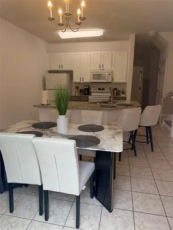 a kitchen with stainless steel appliances kitchen island granite countertop a table chairs and a refrigerator