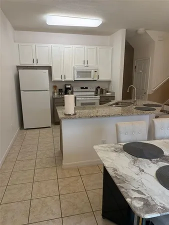 a kitchen with granite countertop a sink a stove and a refrigerator