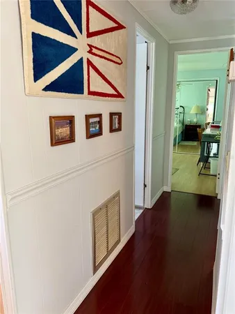 a view of a hallway with wooden floor and a cabinet door