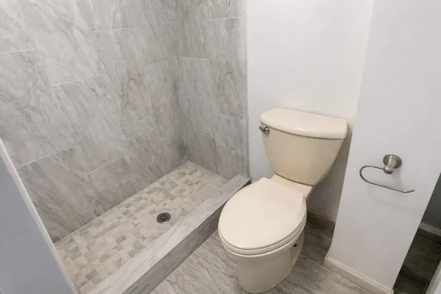a white toilet sitting next to a shower